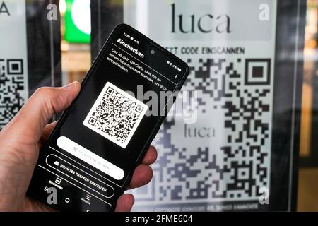 Die Luca-App scannt auf einem Smartphone einen Luca-QR-Code am Eingang zu einem Lebensmittelmarkt in Hannover. Sie können mit Ihrem Mobiltelefon ein- und auschecken und so Corona-Infektionsketten verfolgen. Hannover, 8. Mai 2021 --- Luca-App auf einem Smartphone scannt einen Luca QR-Code am Eingang eines Lebensmittelmarktes in Hannover. Sokann man with the Handy an- and auchecken and the removidly the recognation of Corona-Infection skettens. Hannover, 8.5.2021 Stockfoto