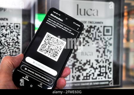 Die Luca-App scannt auf einem Smartphone einen Luca-QR-Code am Eingang zu einem Lebensmittelmarkt in Hannover. Sie können mit Ihrem Mobiltelefon ein- und auschecken und so Corona-Infektionsketten verfolgen. Hannover, 8. Mai 2021 --- Luca-App auf einem Smartphone scannt einen Luca QR-Code am Eingang eines Lebensmittelmarktes in Hannover. Sokann man with the Handy an- and auchecken and the removidly the recognation of Corona-Infection skettens. Hannover, 8.5.2021 Stockfoto