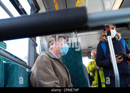 Ältere Mann Passagiere tragen Pappmasken Covid Maske Pandemiemasken Sitzen im Bus in Cardiff Wales UK 2021 Großbritannien KATHY DEWITT Stockfoto