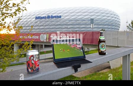 München, Deutschland. Mai 2021. Ein Tablet, mit dem einige Fans die Live-Übertragung des Spiels in der Bundesliga FC Bayern München - Borussia Mönchengladbach verfolgen, steht auf einem Geländer vor der Allianz Arena, in der das Spiel stattfindet. Knapp 20 Fans versammelten sich kurz vor dem Ende des Spiels vor dem Stadion. Der FC Bayern konnte sich am 32. Spieltag den Meistertitel sichern. Quelle: Tobias Hase/dpa/Alamy Live News Stockfoto