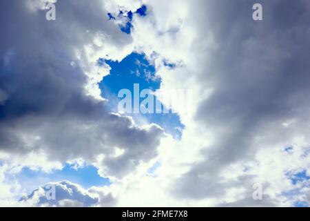 Wabenweise Cumulus-Wolken zeigen Flecken blauen Himmels, die über den Himmel huschen und drohenden Regen bringen. Stockfoto