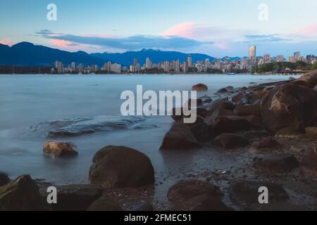 Idyllischer Blick auf die Skyline von Vancouver, B.C. vom felsigen Ufer des Kitsilano Beach über den Burrard Inlet während des Abenduntergangs im Sommer. Stockfoto