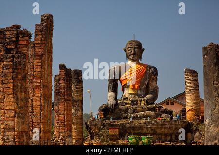 Riesige Steinstatut von buddha, der nach vorne blickt, eingewickelt in orangener Uhrenmonasterie Phonsavan, Laos. Stockfoto