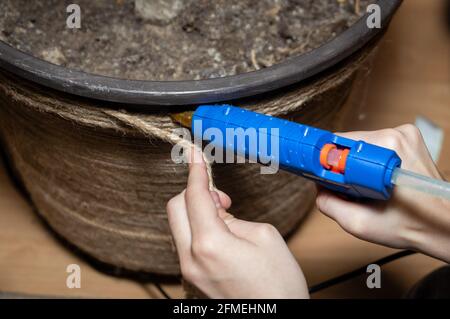 Nahaufnahme des Handwerkers, setzt Künstler die Seildekoration auf den großen Kunststoff-Blumentopf. Stockfoto