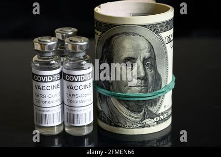 Coronavirus-Impffläschchen und gerollte Dollarscheine auf dunklem Hintergrund. COVID-19-Impfstoff mit US-Geld. Konzept von Impfstoffpreis, Verkauf, Betrug, teuer Stockfoto