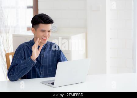 Junge asiatische Geschäftsmann mit Laptop-Computer für Videoanruf online hallo und kommunizieren Arbeit von zu Hause, männliche Konferenz mit Notebook und sagen hallo, s Stockfoto