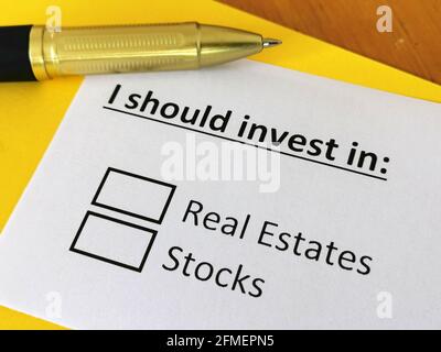 Eine Person beantwortet die Frage nach Investitionen in Immobilien oder Aktien. Stockfoto