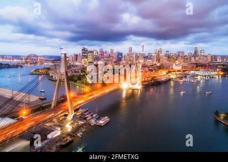 Der Sonnenuntergang über der Stadt Sydney CBD thront hinter der Anzac-Brücke am Hafen von Sydney. Stockfoto