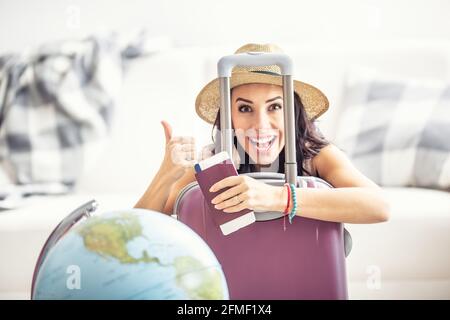 Glückliche Frau zeigt Daumen nach oben, da Reisebeschränkungen sich lockern und sie wieder reisen kann, mit einem Pass und einem Flugticket. Stockfoto