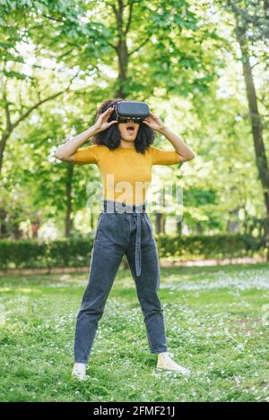 Afro-Frau mit einer Virtual-Reality-Brille in einem Garten. Stockfoto