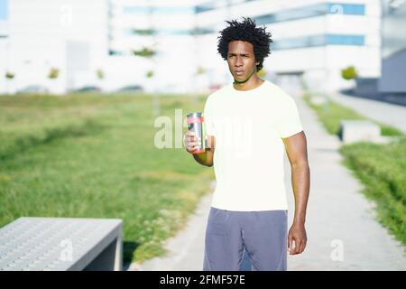 Schwarzer Mann trinkt während der Übung. Der Läufer nimmt eine Trinkpause ein. Stockfoto