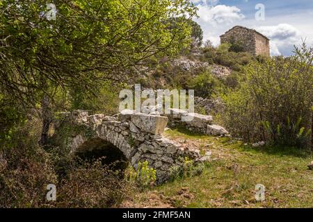 Eine kleine Genoisebrücke über einen Bach in der Balagne Region von Korsika mit einem alten Steinbauernhof in Die Entfernung Stockfoto