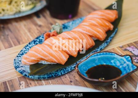 Sushi-Teller aus Lachs-Nigiri mit Sojasauce, serviert auf einer Terrasse. Stockfoto