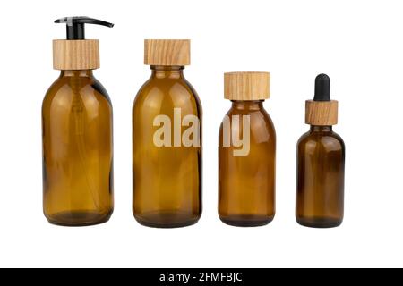 Set aus verschiedenen braunen Glasflaschen mit Holzdeckeln für Kosmetika. Spender mit einem Strohhalm und einer Pipette. Eco-Konzept. Flasche für Lotion, Creme isoliert auf weißem Hintergrund. Holzkorken. Keine Verschwendung. Stockfoto