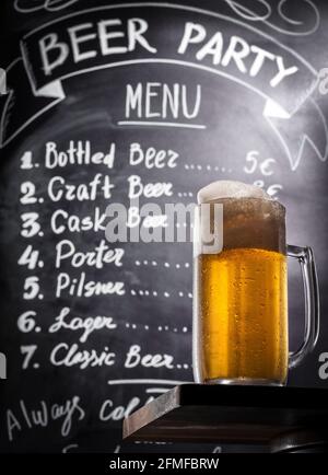 Voller Becher Lagerbier mit Schaumstoff mit Menütext an der Kreidetafel an der Wand. Stockfoto