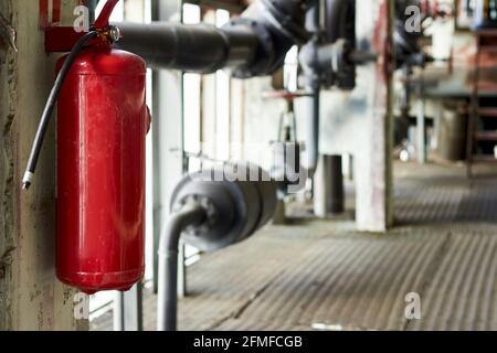 Sicherheitsvorrichtungen für Feuerlöscher im Werk für die Brandschutzanlage. Kohlendioxid-Feuerlöscher mit Manometer an der Wand Stockfoto