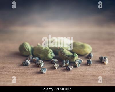 Kardamom-Hülsen und Samen auf einem Holztisch, selektiver Fokus. Stockfoto