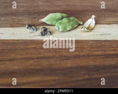Kardamom-Hülsen und Samen auf einem Holztisch, selektiver Fokus. Stockfoto
