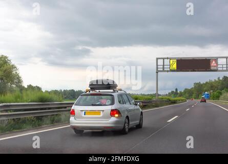 Silbernes Auto mit schwarzem Dach Gepäckkasten fahren auf dem Straße Stockfoto