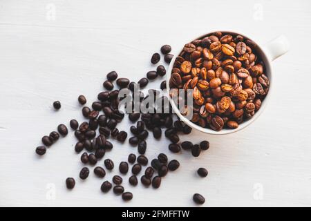 Geröstete Kaffeebohnen in einer Kaffeetasse auf einem weißen Tabelle Stockfoto