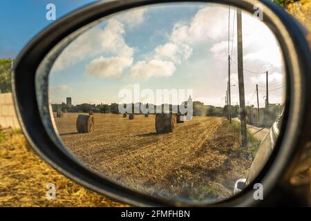 Strohkugeln in einem ländlichen Feld, wie durch die gesehen Spiegelbild eines Autos in der mallorquinischen Stadt Porreres Im Morgengrauen Stockfoto