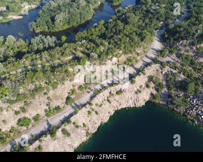 Felsige Ufer des Radon Lake an einem sonnigen Sommermorgen. Luftaufnahme eines alten überfluteten Granitsteinbruchs. Ein malerischer Teich. Stockfoto