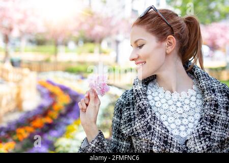 Glückliche junge Rotschopf kaukasische Frau hält rosa Kirschblüte Porträt Stockfoto