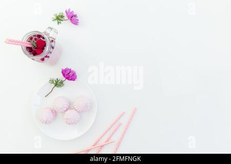 Frucht-Smoothie mit Trinkhalmen, Moorsalbe und rosa Blüten auf weißem Hintergrund. Flach liegend. Stockfoto