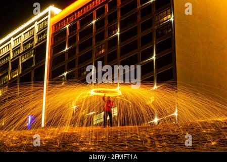 Großes rundes brennendes Feuerwerk funkelt aus der brennenden Stahlwolle. Die Stadt leuchtet bei Nacht. Stockfoto