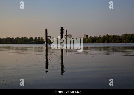 Die Stangen der Anlegestelle auf dem See mit den gegossenen Reflexen Im Wasser Stockfoto