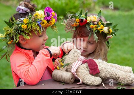 London, Großbritannien, 9. Mai 2021: Die Schulfreunde Emily, 4 Jahre (cremefarbenes Kleid) und Emelia, 5 Jahre (orangefarbene Strickjacke), machen eine Blumenkrone, um den Garden Day zu feiern, und eine für den Teddybären der Klasse. Diese Veranstaltung fand im Chelsea Physic Garden statt und wurde von Floristin Fran Bailey von der Fresh Flower Company geleitet. Anna Watson/Alamy Live News Stockfoto