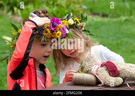 London, Großbritannien, 9. Mai 2021: Die Schulfreunde Emily, 4 Jahre (cremefarbenes Kleid) und Emelia, 5 Jahre (orangefarbene Strickjacke), machen eine Blumenkrone, um den Garden Day zu feiern, und eine für den Teddybären der Klasse. Diese Veranstaltung fand im Chelsea Physic Garden statt und wurde von Floristin Fran Bailey von der Fresh Flower Company geleitet. Anna Watson/Alamy Live News Stockfoto