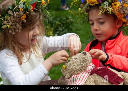 London, Großbritannien, 9. Mai 2021: Die Schulfreunde Emily, 4 Jahre (cremefarbenes Kleid) und Emelia, 5 Jahre (orangefarbene Strickjacke), machen eine Blumenkrone, um den Garden Day zu feiern, und eine für den Teddybären der Klasse. Diese Veranstaltung fand im Chelsea Physic Garden statt und wurde von Floristin Fran Bailey von der Fresh Flower Company geleitet. Anna Watson/Alamy Live News Stockfoto