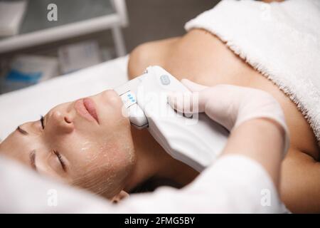 Frau Klientin liegt im Schönheitssalon Zimmer, erhält Ultraschall smas nicht-chirurgischen Gesichtslift von professionellen Kosmetikerin Arzt, Hand hält Ultraschall Stockfoto