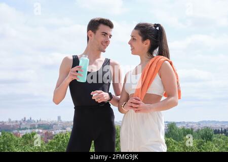 Junges, sportliches Paar, das sich ansieht und lächelt, steht in einem Park. Fitness im Freien. Stockfoto