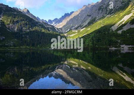 Die schöne Popradske pleso, umgeben von der Tatra, in der Abendsonne. Die Landschaft spiegelt sich im See wider. Slowakei. Stockfoto