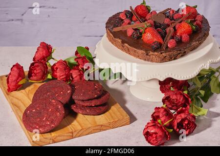 Eine Nahaufnahme eines herzförmigen Brownie-Kuchens und rotem Samt Kekse mit Rosen zum Muttertag Stockfoto