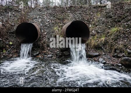 Bundsteg. Abfluss von Wasser aus einem Straßenüberlauf (Wasserentsorgung, Sturmabfluss), zwei Leitungen und langsam fließendes Wasser (direkter Abfluss) Stockfoto