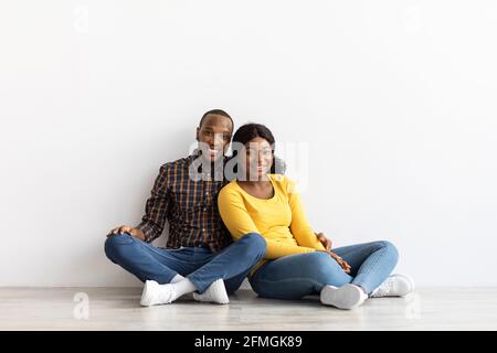 Porträt Eines Glücklichen Schwarzen Paares, Das Auf Dem Boden In Leer Sitzt Flach Stockfoto