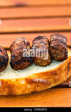 Ein vertikaler Schuss von Fleischrollen, die Mici oder mititei genannt werden Auf der Scheibe eines Brotes Stockfoto