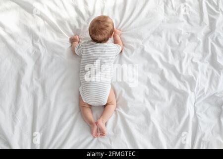 Babyentwicklungskonzept. Draufsicht Auf Das Kind, Das Auf Dem Bett Kriecht Stockfoto