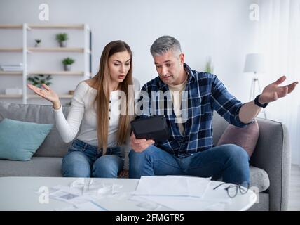 Finanzkrise. Unglückliches Ehepaar, das Rechnungen und Ausgaben berechnet und nicht in der Lage ist, Schulden zu Hause zu bezahlen Stockfoto