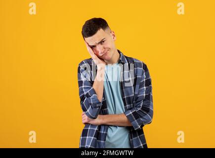 Porträt von verärgerten kaukasischen Kerl in Freizeitkleidung Blick auf die Kamera in Frustration, orangen Studio-Hintergrund Stockfoto