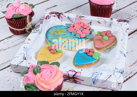 Butterkekse, dekoriert mit rollendem Fondant und königlicher Glasur. Umgeben von Cupcakes und Keksen. Geschrieben in portugiesischer Mutter, Ich liebe dich. Stockfoto