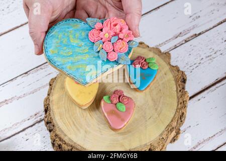 Hand mit einem Shortbread-Keks, dekoriert mit rollendem Fondant und königlicher Glasur. Stockfoto