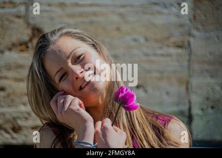 Junge Frau, die sehr glücklich aussieht, mit einer Blütenzentenblume in der Hand Stockfoto