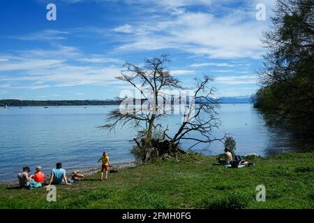 Menschen genießen die Sonne am Starnberger See in Feldafing mit Blick auf die schneebedeckten Alpen. Stockfoto