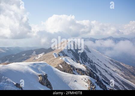 Schneebedeckte Berggipfel umgeben von Wolken und Nebel Stockfoto