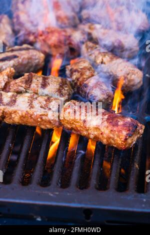 Ein vertikaler Schuss von Fleischrollen, die Mici oder mititei genannt werden Auf dem Grill mit aufsteigendem Rauch Stockfoto