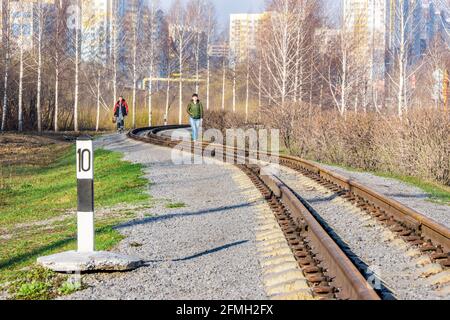 Kemerowo, Russland - 29. april 2021. Eine kurvenreiche Schmalspurbahn, entlang der die Menschen von den Wohngebäuden aus laufen Stockfoto